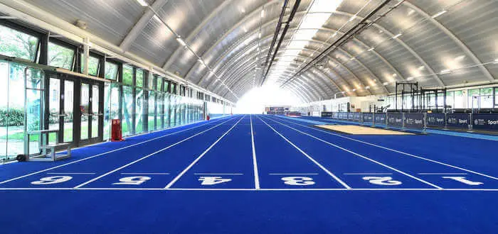 The blue indoor sprint track at Brunel's Indoor Athletics Centre, lanes marked and numbered